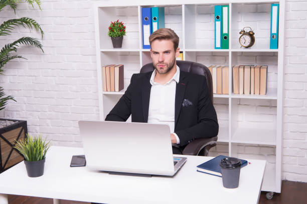 Portrait of confused young businessman with coffee sitting in office and holding paper stock photo