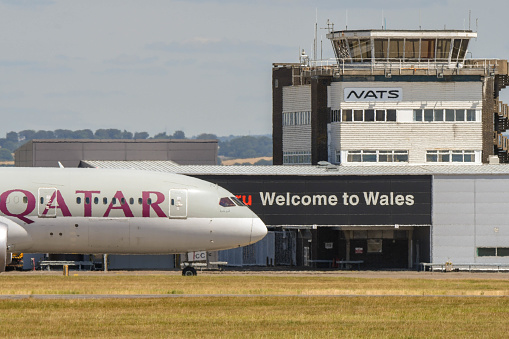 Cardiff, Wales - July 2018: Qatar Airways Boeing 787 Dreamliner arriving at Cardiff Wales Airport. In the background is the terminal building with a \