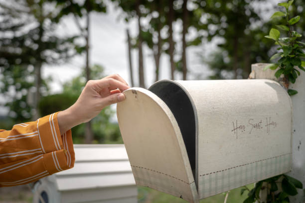 Checking mailbox - hand action. A hand of personal is opening the classical vintage style mailbox to check to letter inside. The mailbox is installed in front of the house, surrounded by garden environment. mailbox photos stock pictures, royalty-free photos & images