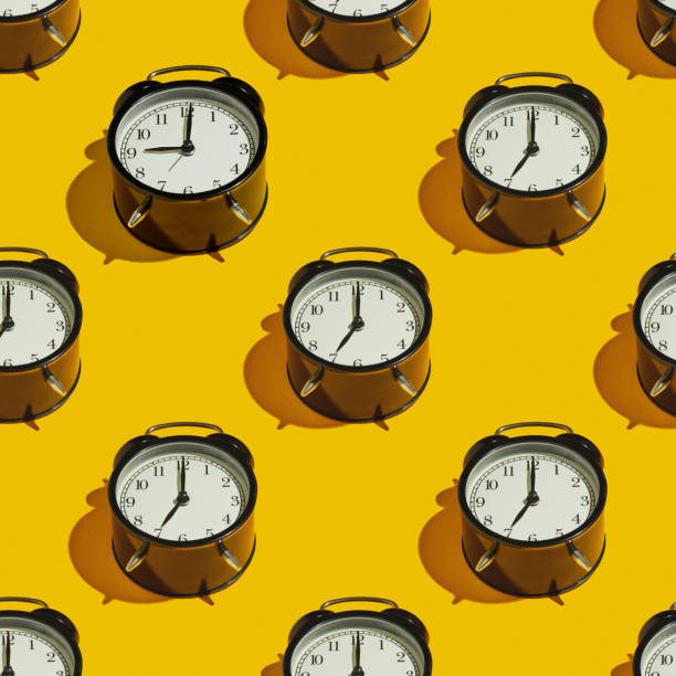istock Pattern Black alarm clock with a hard shadow on a yellow background 1254571278