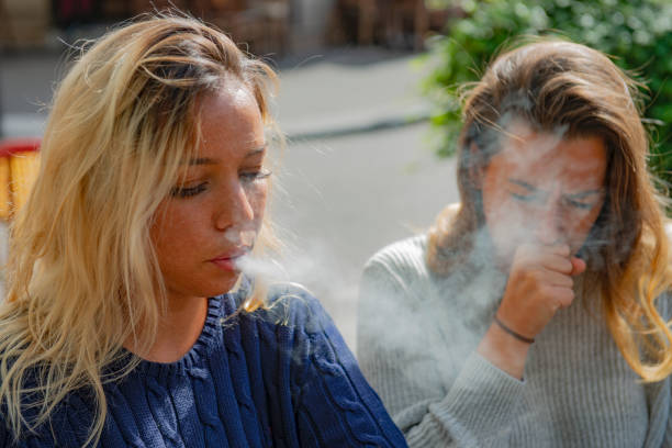 girl smoking besides a non smoker - non polluting imagens e fotografias de stock