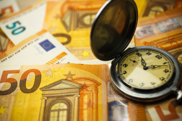 Time is money concept with euros and golden pocket watch. Close up. Selective focus