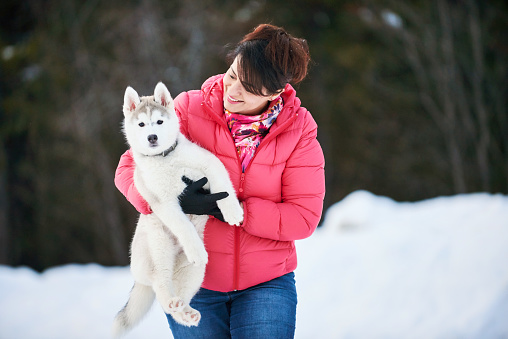 Shot of a woman with her husky dog outdoors on a winter day