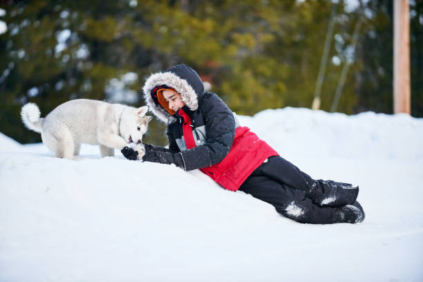 Shot of a young boy playing with his pet husky dog in snow outdoors
