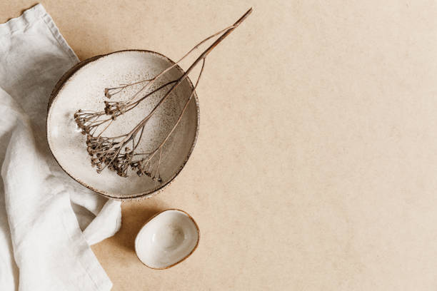 istock Minimalist ceramic bowl with dry plant over kraft paper background. Copy space, flat lay. 1254575865