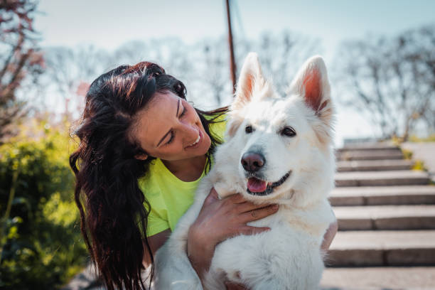 Young woman holding her dog and looking at him happily.