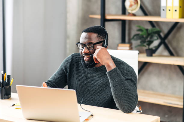 ラップトップを使用してヘッドセットを持つアフリカ系アメリカ人の男 - working at home headset telecommuting computer ストックフォトと画像