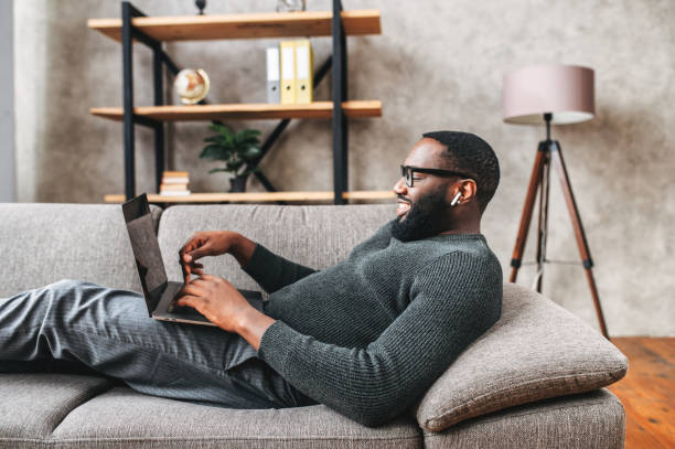 istock African-American guy lays on sofa with laptop 1254577036