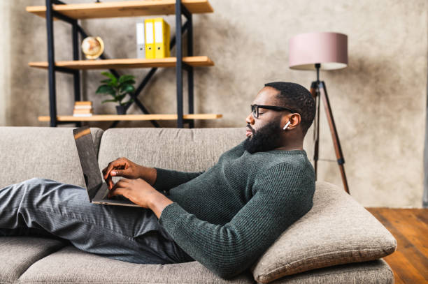 istock African-American guy lays on sofa with laptop 1254577037