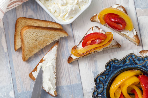 fatias de pão torrado com queijo branco macio e pimentões fritos. café da manhã simples, vista superior - antipasto roasted pepper bell pepper pepper - fotografias e filmes do acervo