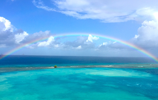 Turquoise water off the coast of Aruba with a rainbow in the sky