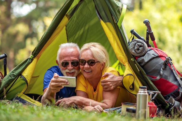 テントの前に座っているシニアカップル - bag senior adult outdoors friendship ストックフォトと画像