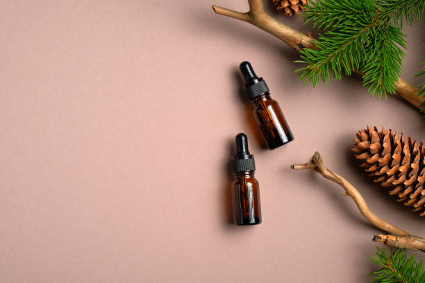 istock Flat lay composition with bottles of conifer essential oil on beige background with copy space. Natural organic cosmetics with pine tree branches and cones. Top view. 1254581630