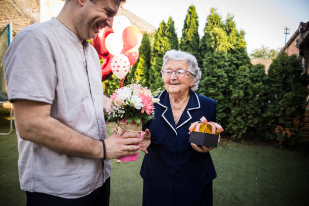 happy mid adult man holding flowers for the happy elderly birthday girl - 96 well imagens e fotografias de stock