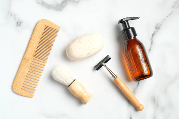 istock Flat lay composition with bath accessories and shaving tools for man on marble background. Top view wooden hair comb, handmade soap, shaving brush, razor, shampoo bottle. 1254585701