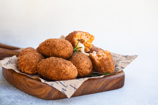 Supplì - italian snacks consisting of rise with tomato sauce and mincemeat, filled with peace of mozzarella, soaked in eggs, coated with bread crumbs and deep-fried. Roman cuisine. White background.