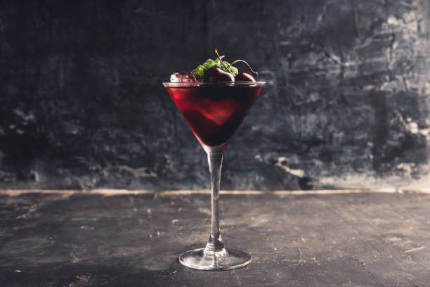 cóctel de cereza en vaso de martini con bayas y hojas de menta - black cherries fotografías e imágenes de stock