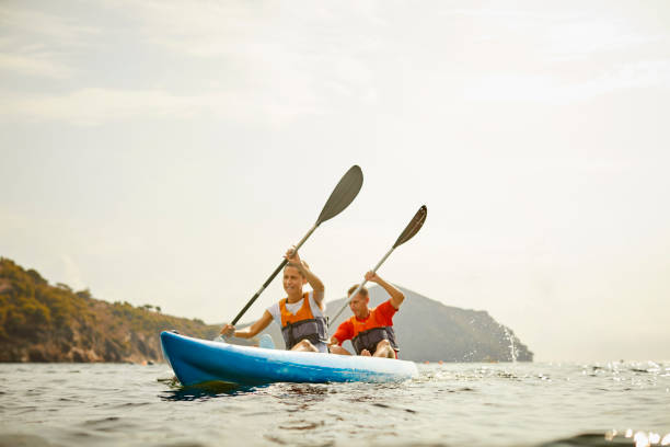 istock Man And Woman Kayaking On River Against Clear Sky 1254587519