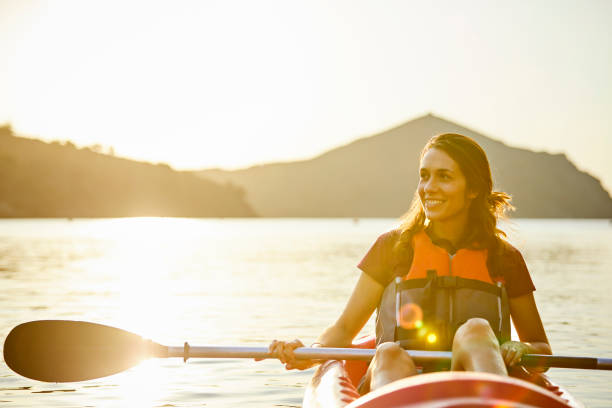 istock Smiling Woman Kayaking On River During Sunset 1254587531