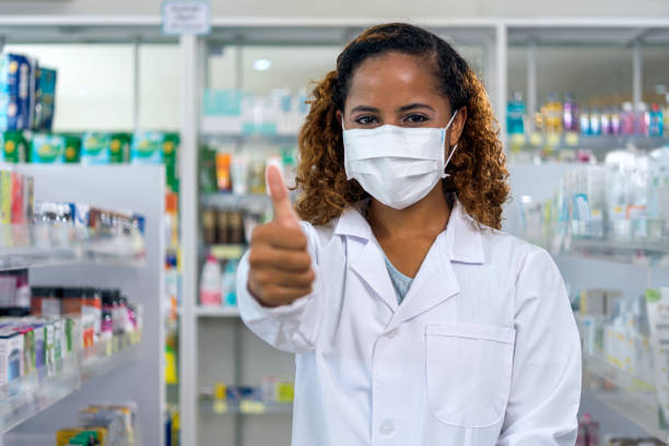 Wearing protective mask is the best. Female Pharmacist wearing protective mask and smiling. resilience photos stock pictures, royalty-free photos & images