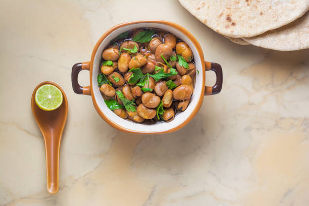 ful medames - schale aus ägyptischen fava bohnen mit zitrone, kümmel, gemüse - broad bean bean bowl brown stock-fotos und bilder