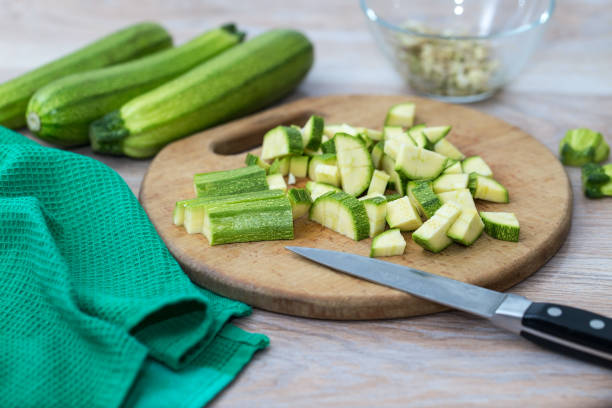 courgettes vertes, tranchées sur une planche à découper, légumes frais pour la cuisson à la maison - zucchini vegetable chopped portion photos et images de collection