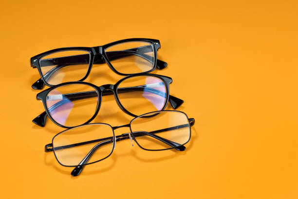 istock Different types of glasses on a yellow background close up. Glasses with rectangular and round frames. Layout for design. Space for text and free space near the object. 1254595120
