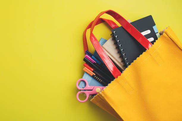 istock Learning supplies with notebooks, coloured pens and scissors in yellow bag 1254598656
