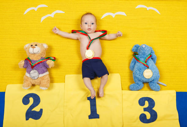 Full length portrait of a little child is standing on a place podium in first place. Handsome boy is cheering and standing on victory podium with medal. Funny baby. First place winner. Success concept