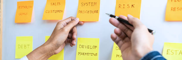 istock Two creative Business people meeting and planning use post it note on board to share idea, Analysis data charts and graph with teamwork strategy brainstorming 1254602505