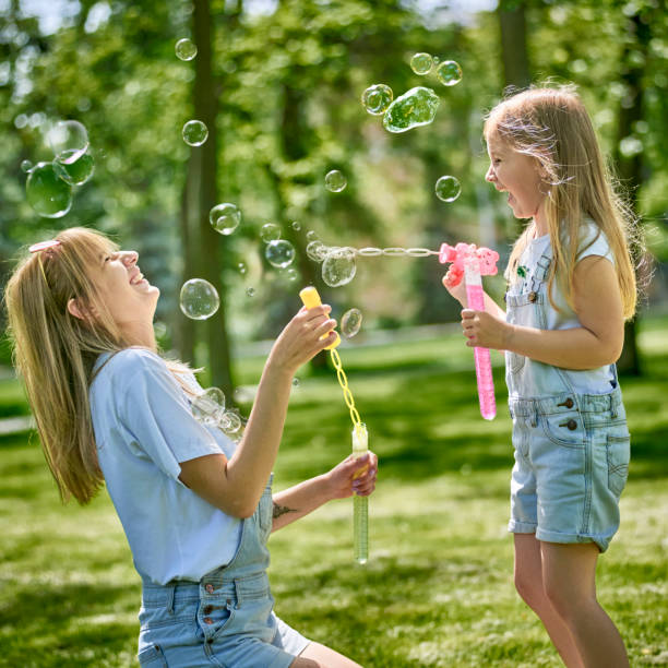 istock Smiling mother and daughter blowing bubbles in nature 1254604279