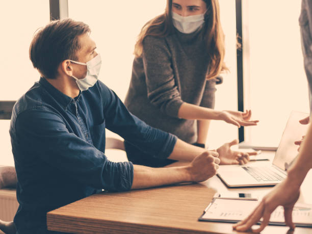 istock employees in protective masks discussing online information 1254605307