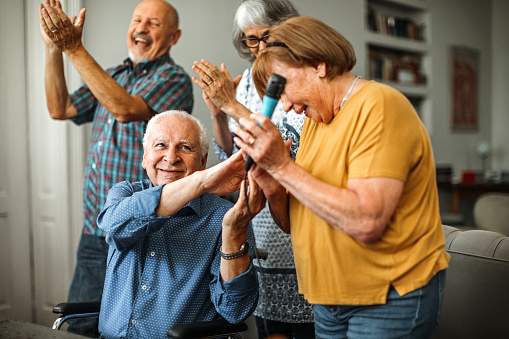 Senior people celebrating in nursing home, singing karaoke