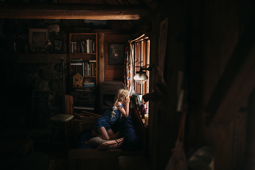 An elementary aged child enjoys a family vacation in an isolated log cabin in the woods in the Pacific Northwest.  Shot in Washington state, USA.