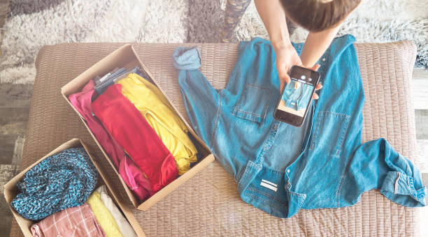 kobieta robi zdjęcie dżinsowej koszuli na smartfonie, aby sprzedać ją w sklepie internetowym. - fashion industry textile man made material green zdjęcia i obrazy z banku zdjęć