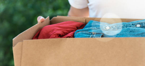 istock Man holding cardboard box with clothes inside. Concept donation and reuse or recycle your used clothes 1254612640