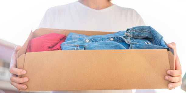 istock Man holding card box with used clothes inside. Donation concept 1254612645
