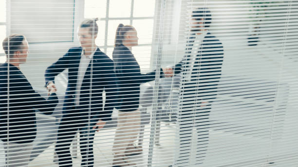 istock through the blinds. young business people shaking hands with each other 1254618781