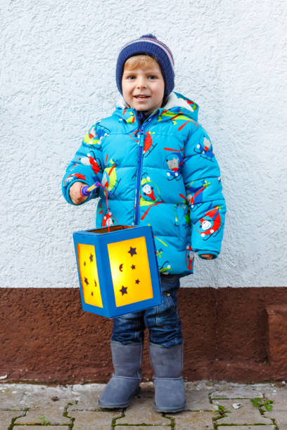 istock Little kid boy holding selfmade lanterns for a Halloween or St. Martin procession. Beautiful healthy cute child happy about children and family parade in kindergarten. German tradition Martinsumzug 1254618892