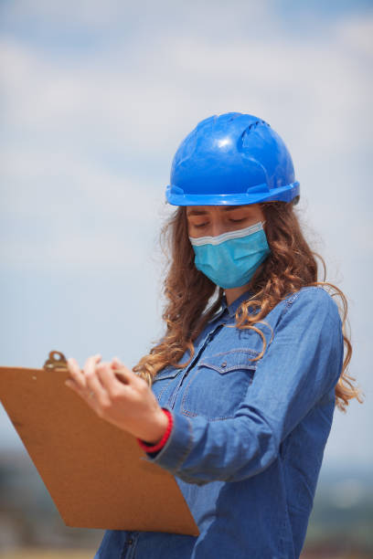 istock young woman engineer wearing face mask and holding clipboard with documents 1254621720
