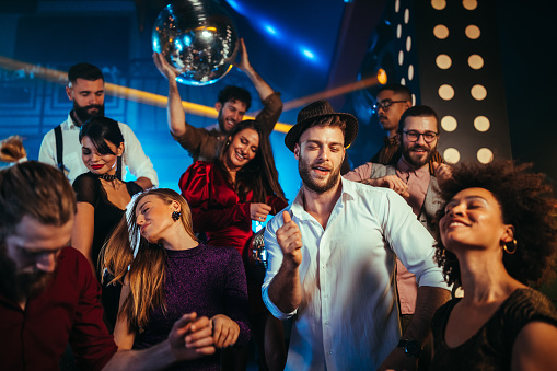 Group of energetic young people dancing at a party in a nightclub