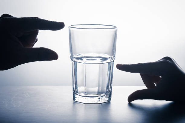 Glass Half Full Glass half full water with hands measure in different position, mindset of positive thinking in crisis and opportunity concept pessimism photos stock pictures, royalty-free photos & images