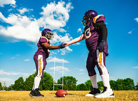 Two Junior Football players during practice game at the outdoor field. Handshake before the kick.