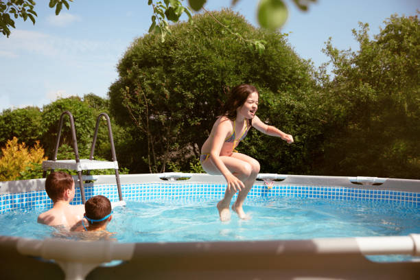 istock Girl jumping into backyard pool 1254624212