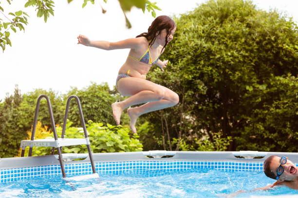istock Girl jumping into backyard pool 1254624263