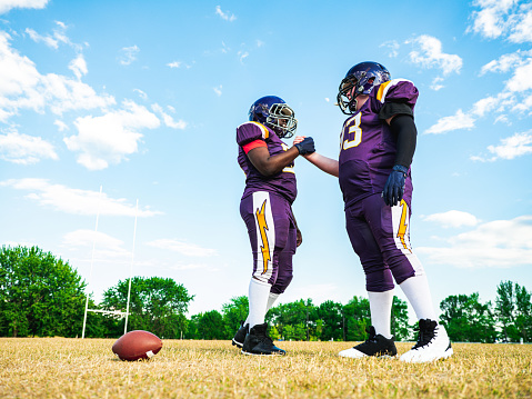 Two Junior Football players during practice game at the outdoor field. Handshake before the kick.