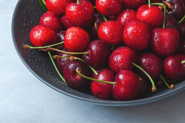 istock Cherry with leaf on plate and water dropsend on grey stone table 1254625416