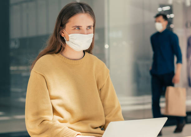 istock serious young woman in a protective mask using a laptop 1254626239