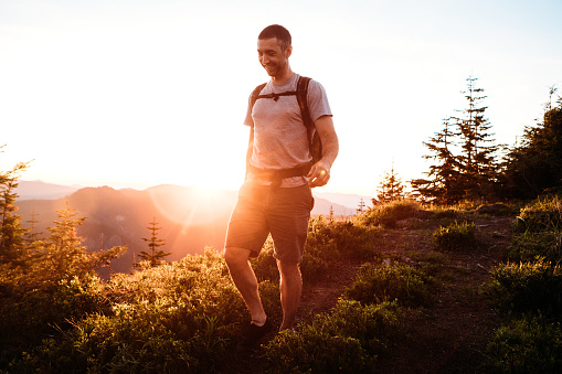 A mid-adult Caucasian man hikes a mountain near Mount Rainier national park on a clear sunny day, the setting sun casting warm colors on the crisp scene.  Part of the natural beauty of the Pacific Northwest in Washington state, USA.