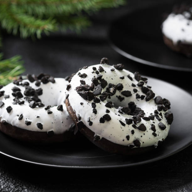 istock Doughnuts with white icing and chocolate chips in a black plate on the black kitchen table. Delicious dessert 1254627793